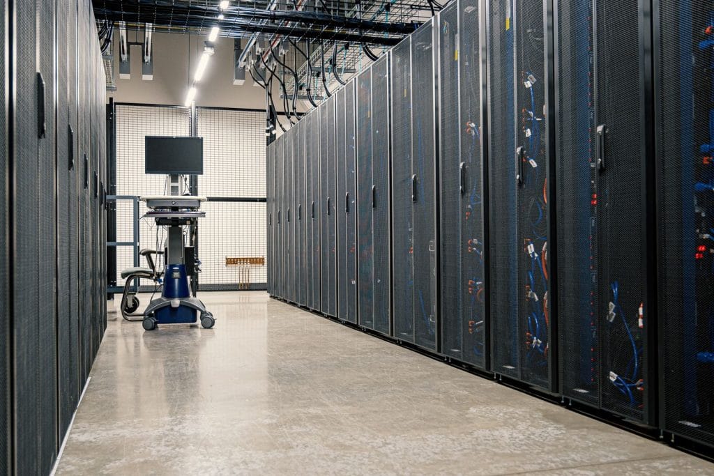 Allée d’une salle de serveurs avec des baies informatiques éclairées