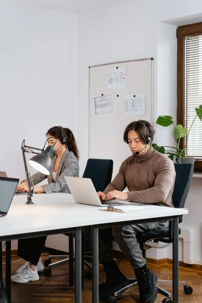 Deux collaborateurs avec casque et micro passent des appels depuis leur ordinateur portable dans un bureau